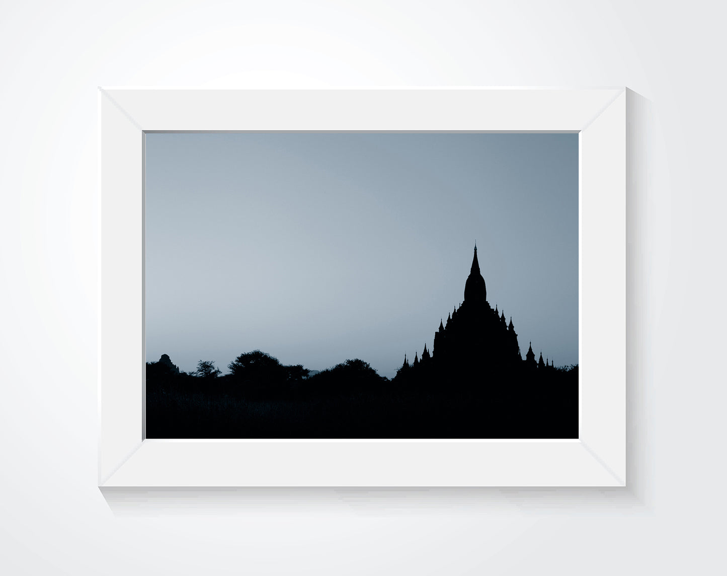 A framed photograph of ruins hung on a white wall.