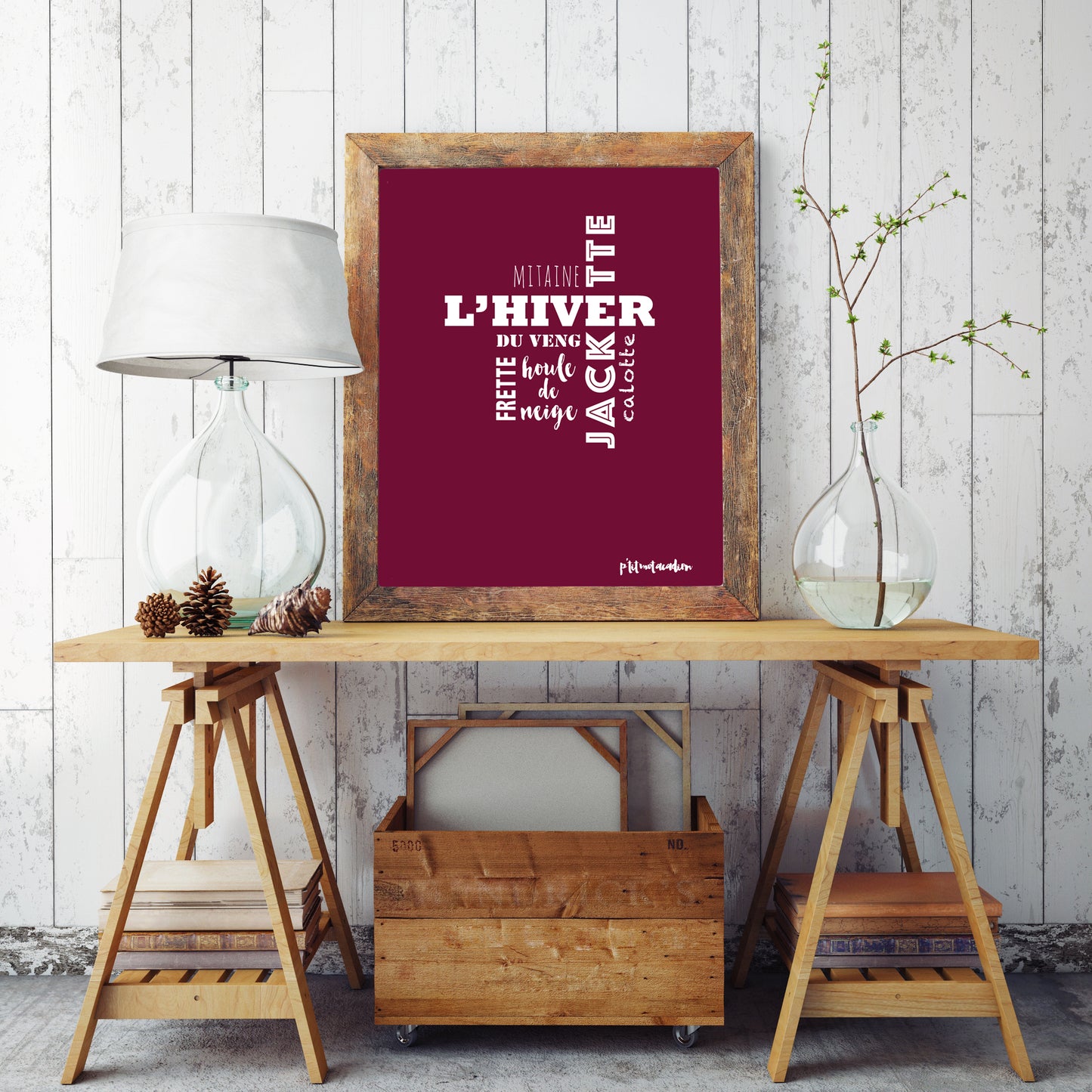 A red framed Acadian words print about winter sitting on a table.