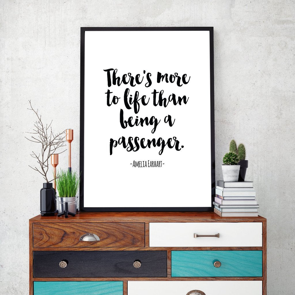 A quote by Amelia Earhart saying "There is more to life than being a passenger" printed and framed sitting on a colourful bureau.