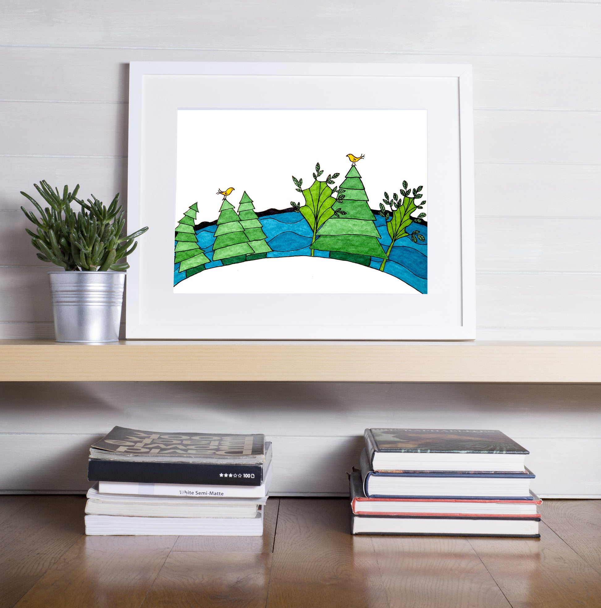 A printed illustration of a Nova Scotia location, framed and sitting on a shelf just above books.