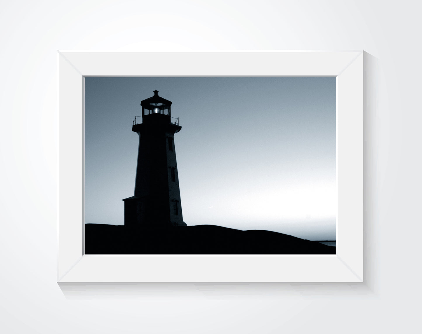 Framed lighthouse photograph hung on a white wall.