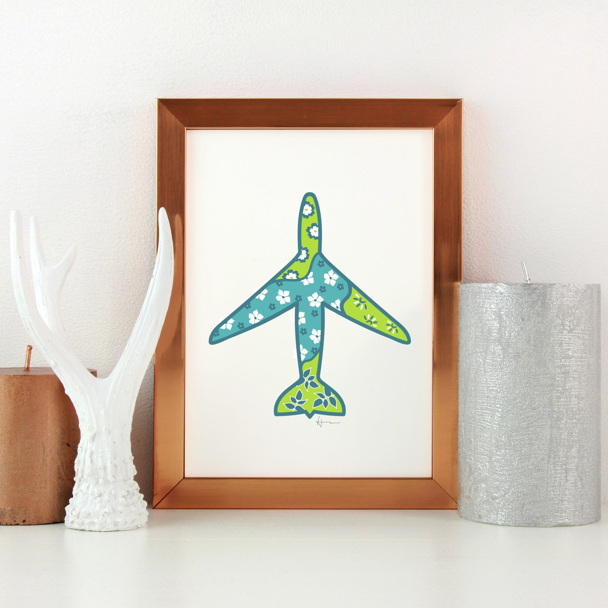 framed airplane illustration on a desk or white table with decorations on each side.