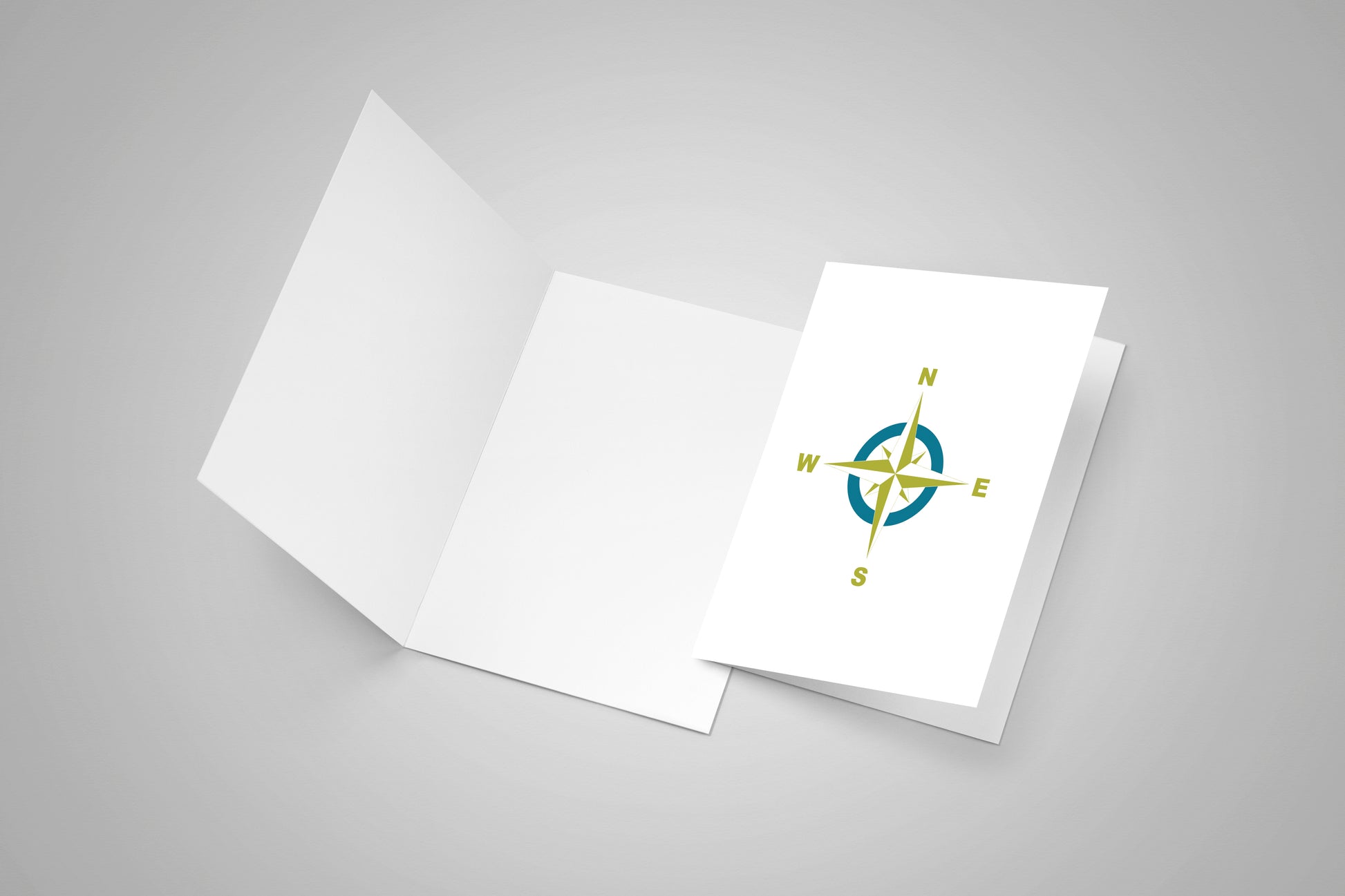 A blank card and second card with a compass rose on the front in teal and lime colours.