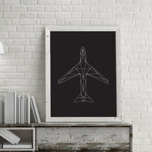 A modern geometric illustration of an aircraft printed and framed on a modern desk with a lamp hanging near.