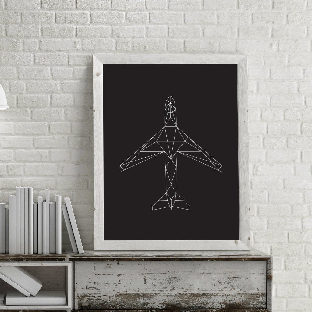 A modern geometric illustration of an aircraft printed and framed on a modern desk with a lamp hanging near.