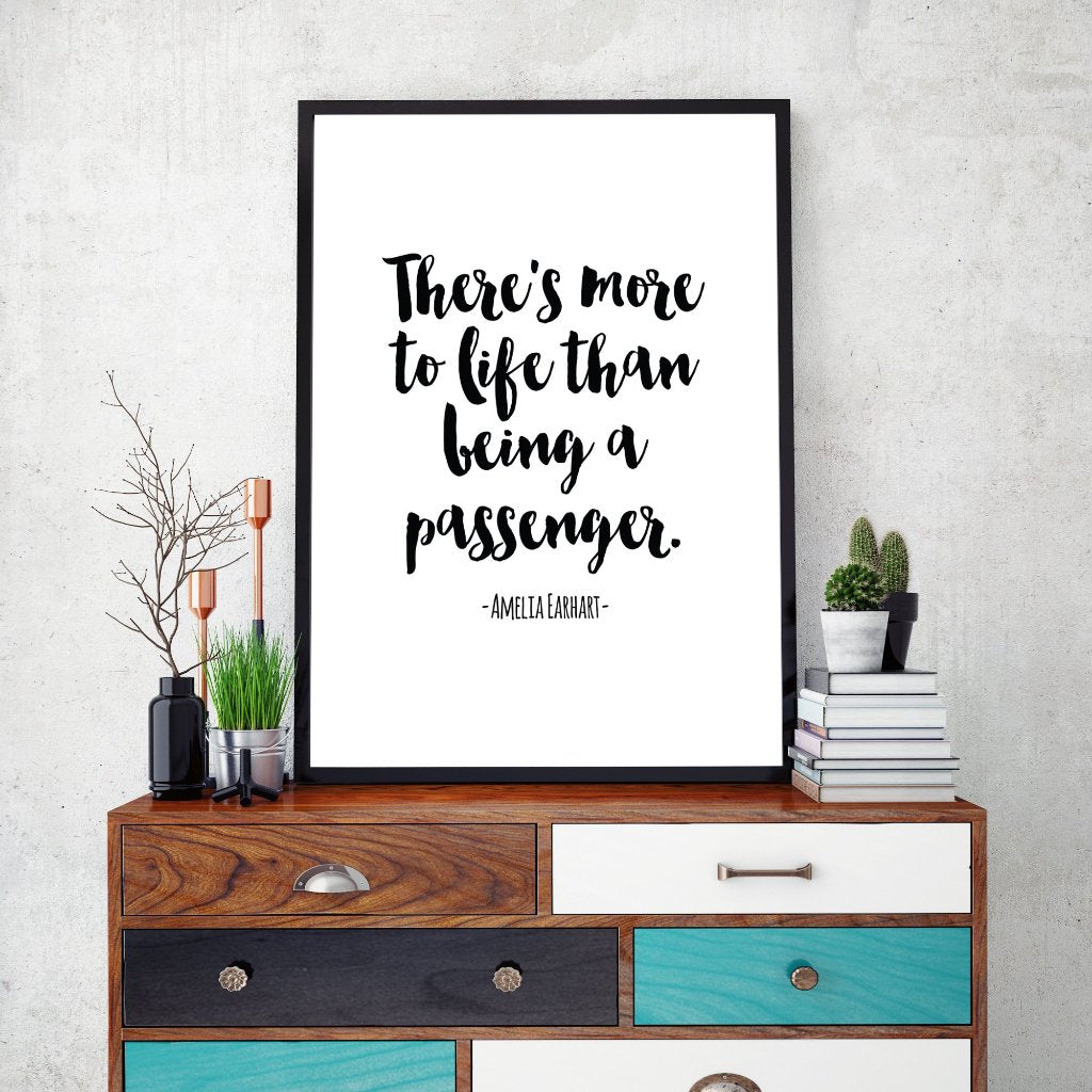 A quote by Amelia Earhart saying "There is more to life than being a passenger" printed and framed sitting on a colourful bureau. 